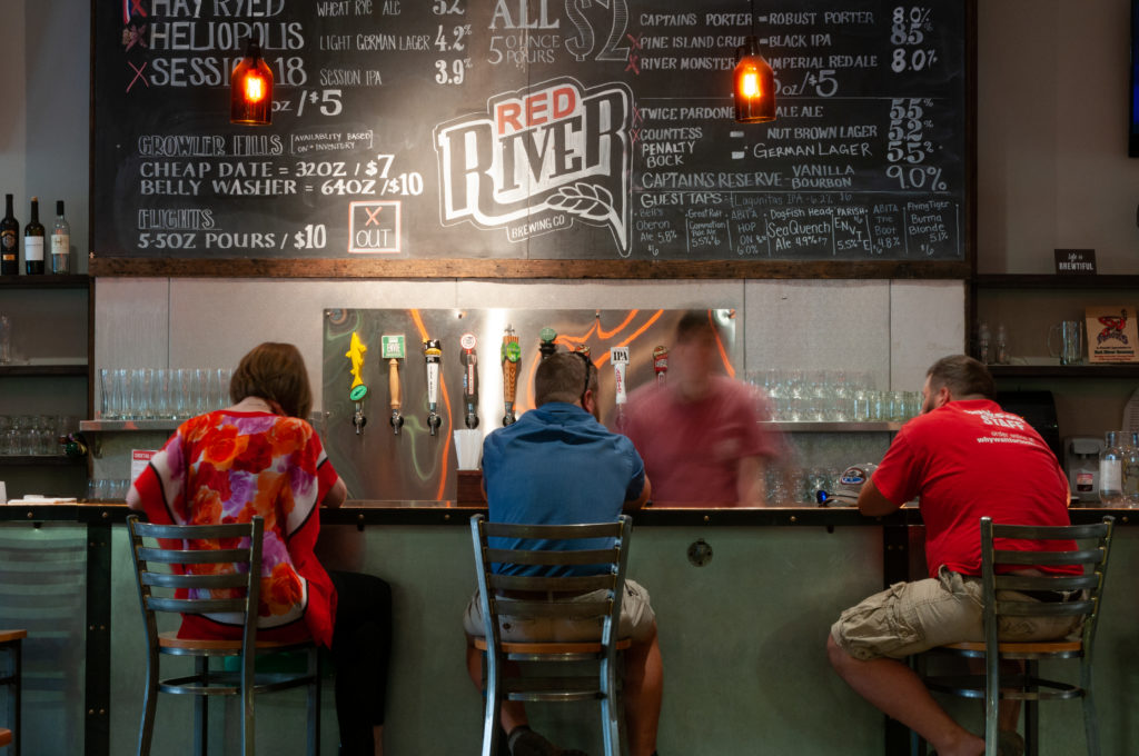 Patrons sit at the bar at Red River Brewery