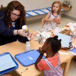 Tech student helping kids with arts and crafts.
