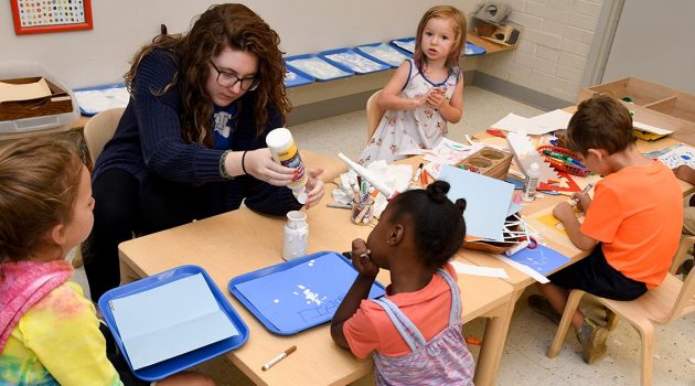 Tech student helping kids with arts and crafts.