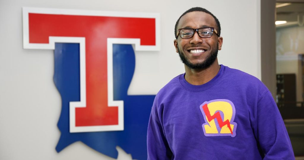 Nicholas Cobb standing in front of the Louisiana Tech University state and T logo.